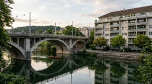 Pont en béton et immeuble d’appartements au bord d’une rivière calme.